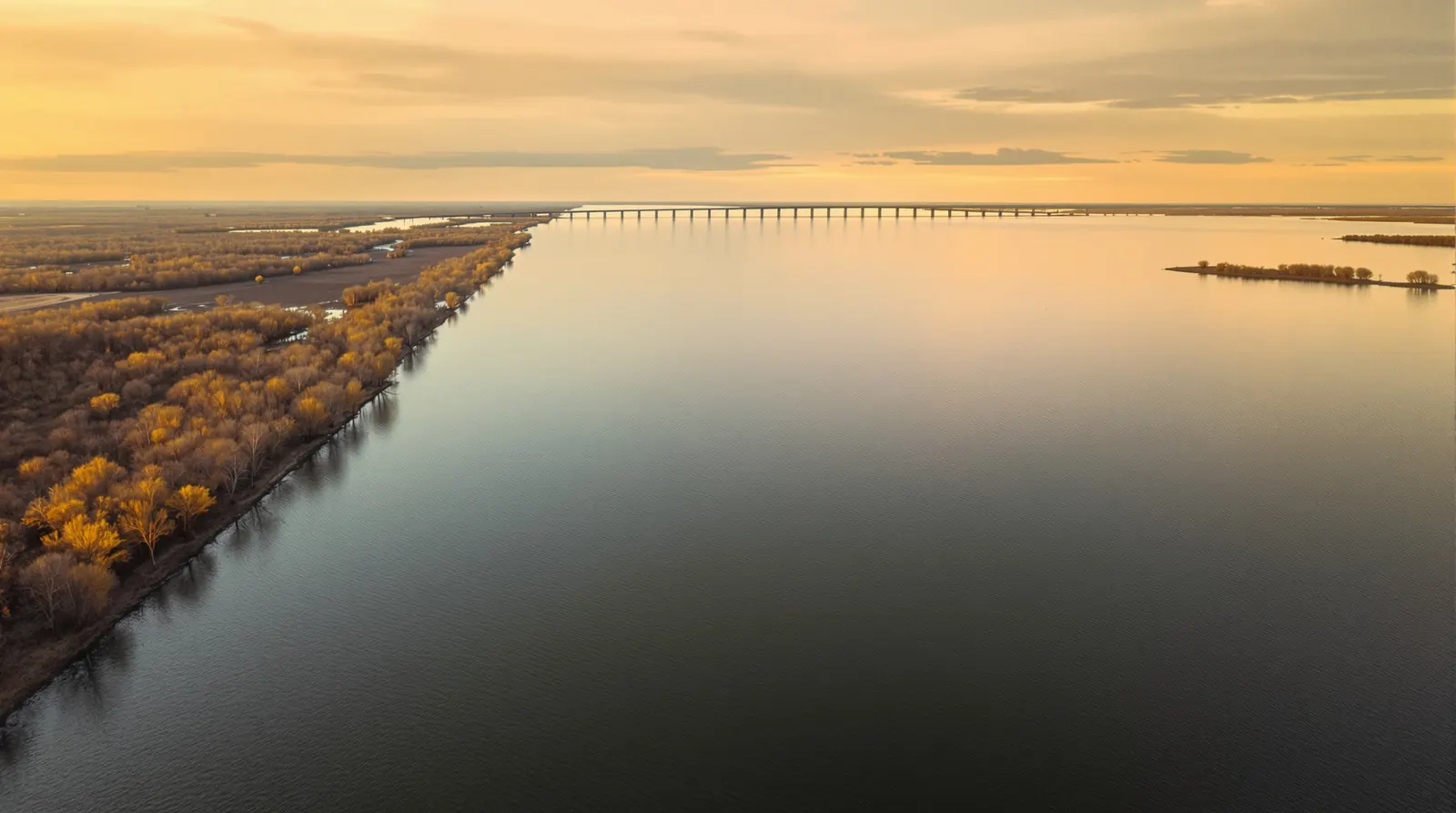 A golden-hour aerial of the vast, flat Bois d'Arc Lake, wide open water reaching a long, low wooded shoreline.