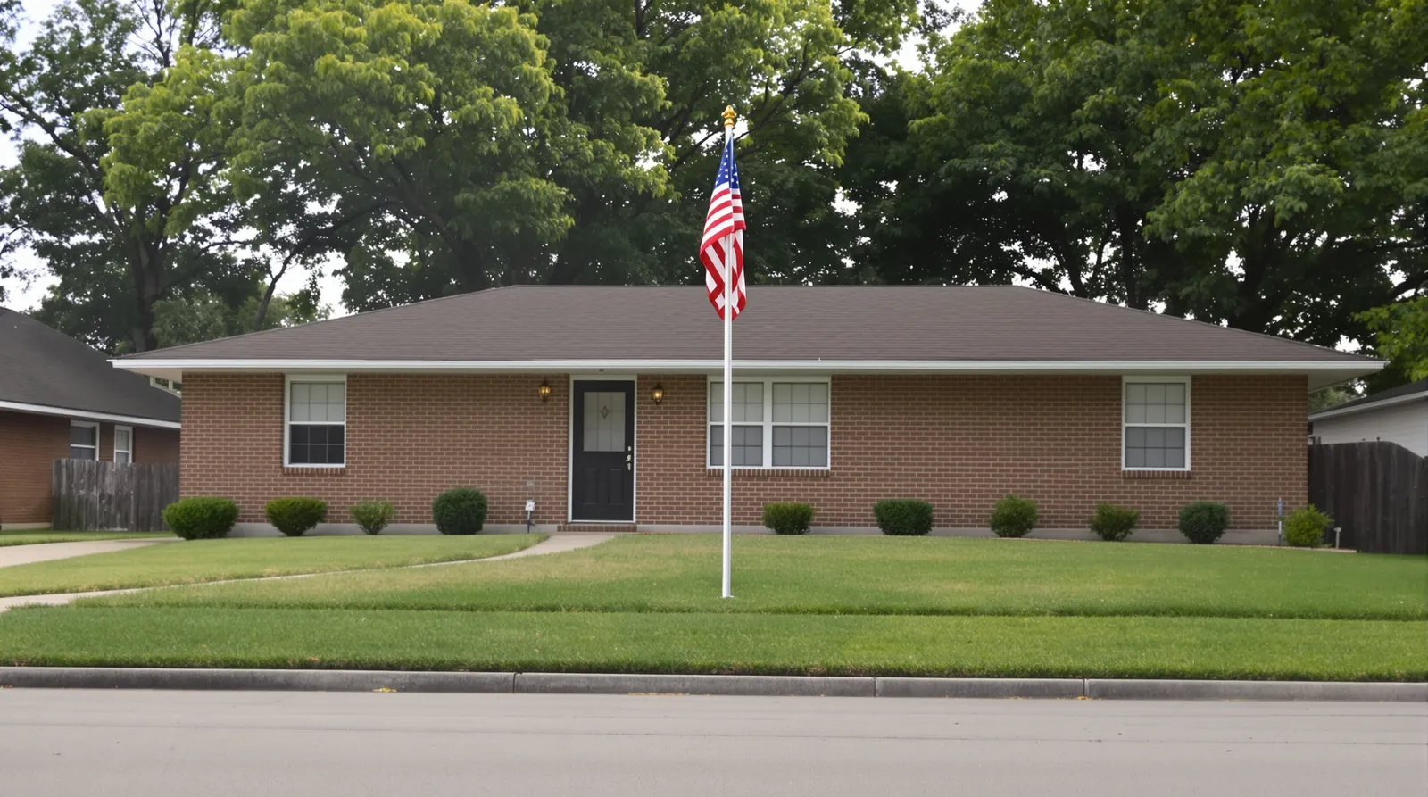 A single well-kept one-story Texas brick home with a modest American flag on a flagpole in the front yard under soft morning light.
