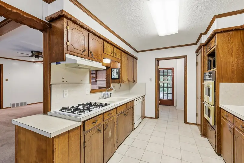 Galley kitchen with wood cabinets, laminate counters, gas cooktop and dishwasher