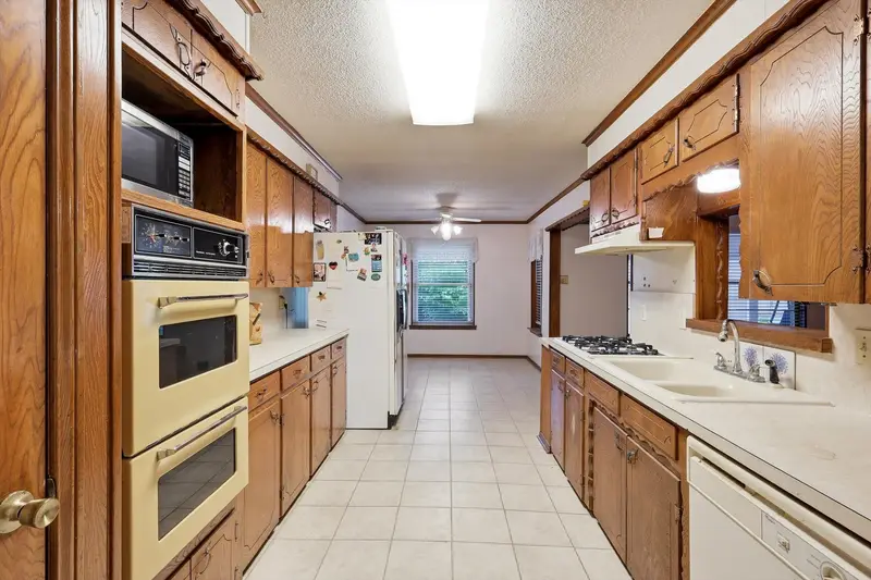 Kitchen with double wall ovens, wood cabinets, double sink and a window over the counter