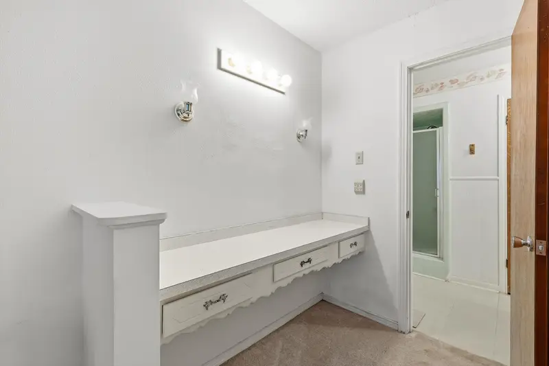 Built-in makeup vanity and dressing area in the primary suite with wall sconces