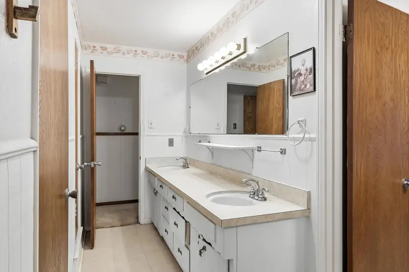 Primary bath with a double-sink vanity, cultured-marble top and large mirror