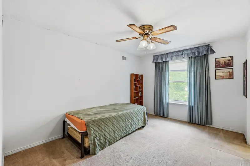 Secondary bedroom with a draped window, ceiling fan and carpet