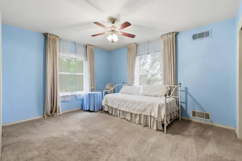 Bedroom with blue walls, two draped windows and a white iron daybed