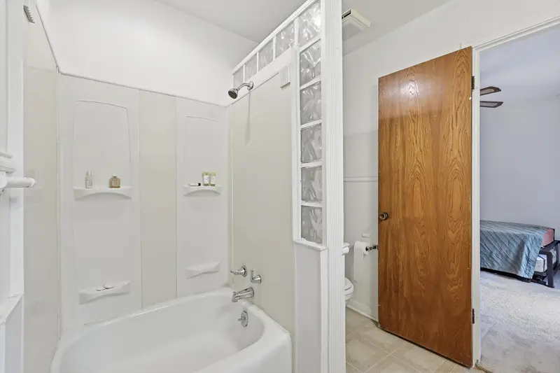 Bathroom with a tub-shower, glass-block accent wall and wood door
