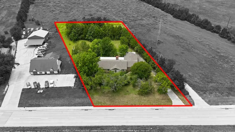 Angled aerial with the approximate property boundary outlined in red, showing the home, trees and open field