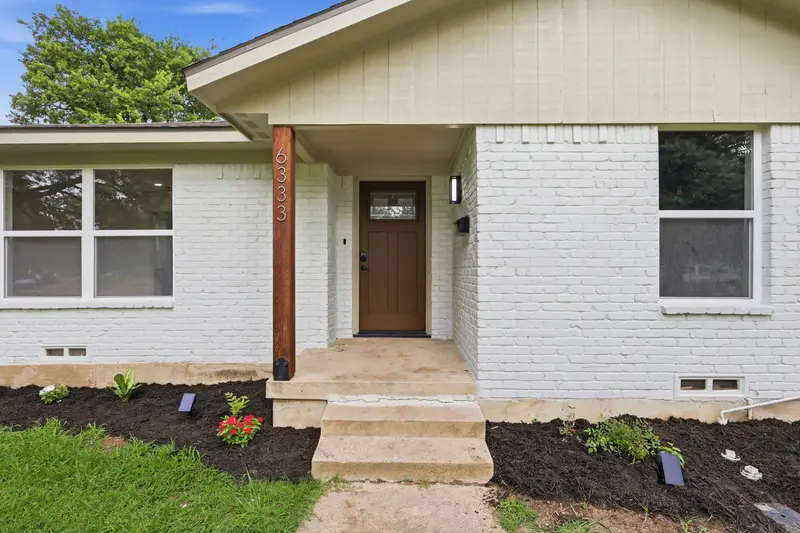 Craftsman front door with cedar porch post, house numbers and fresh flower beds