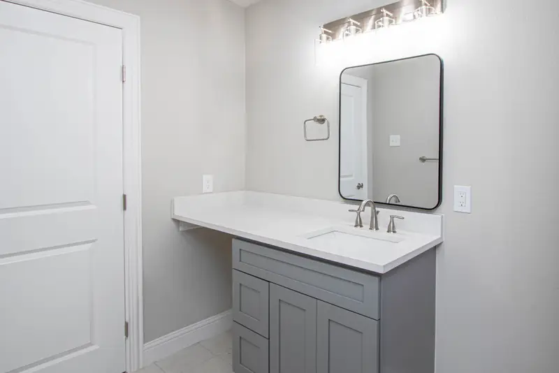 Updated bath with a gray shaker vanity, white quartz top and a black-framed mirror