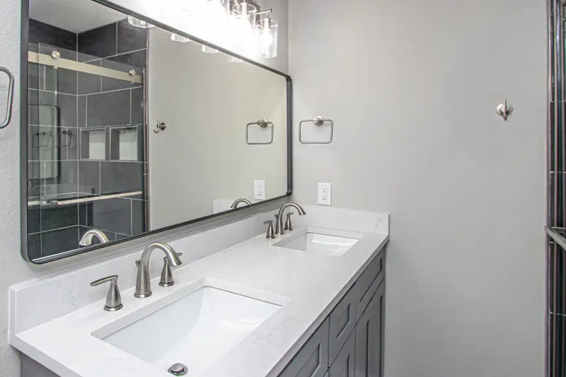 Double vanity with white quartz counters, dual undermount sinks and a large black-framed mirror