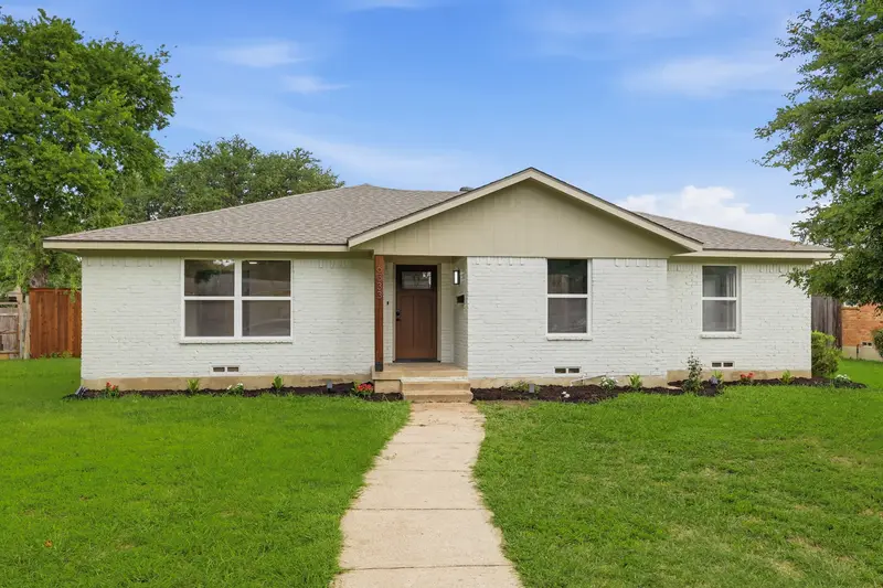 Wide front view of the white brick single-story home with a central craftsman entry