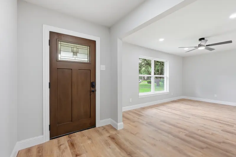 Craftsman front door opening to a bright front room with wood-look floors