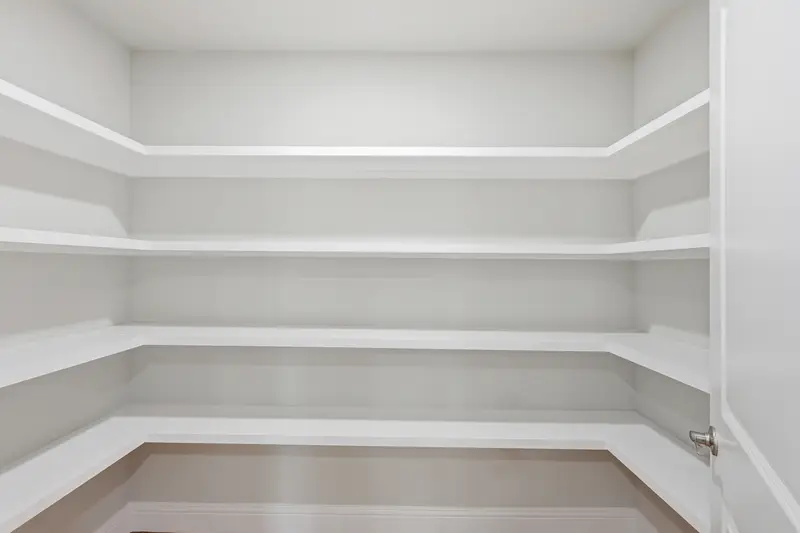 Walk-in pantry with white wrap-around shelving and wood-look floor