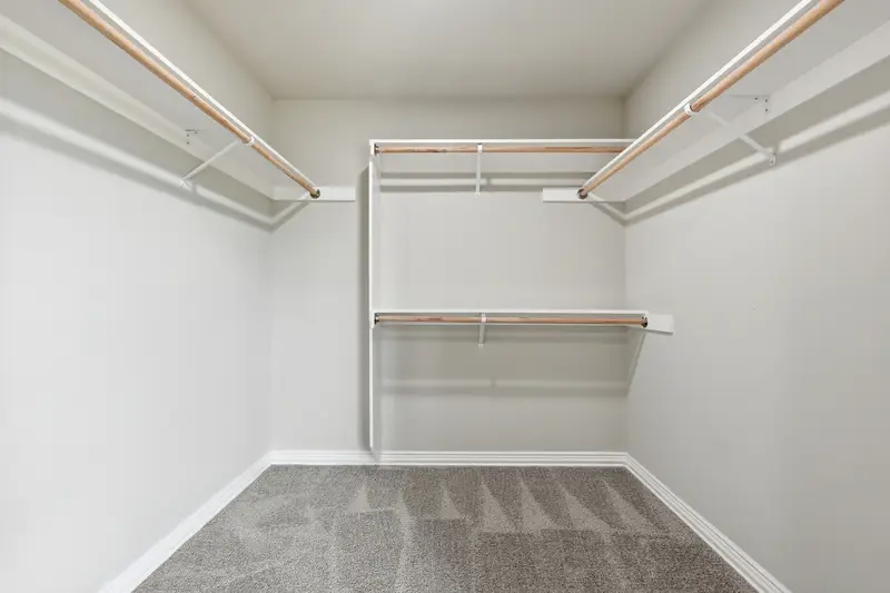 Carpeted walk-in closet with wood closet rods and white shelving