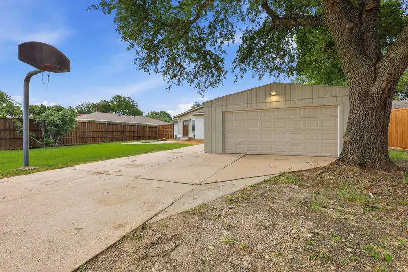 Detached two-car garage with a basketball goal and concrete court in the fenced yard