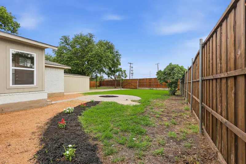 Side yard with fresh flower beds, cedar privacy fence and the detached garage