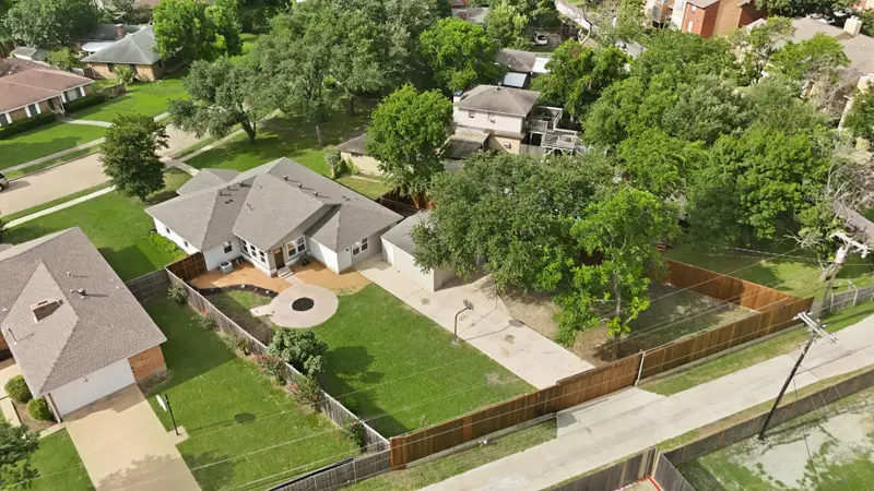 Angled aerial of the home, fenced backyard, sport court and detached garage