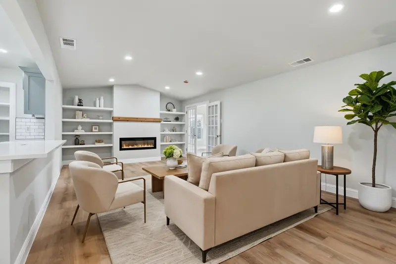 Virtually staged living room with a sofa and accent chairs by the electric fireplace and built-in shelves