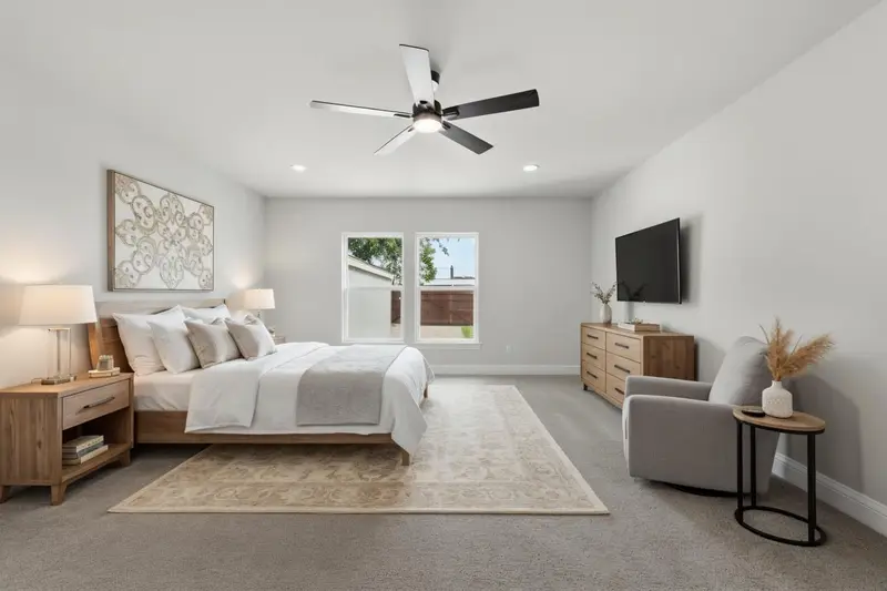 Virtually staged primary bedroom with a king bed, dresser and sitting chair