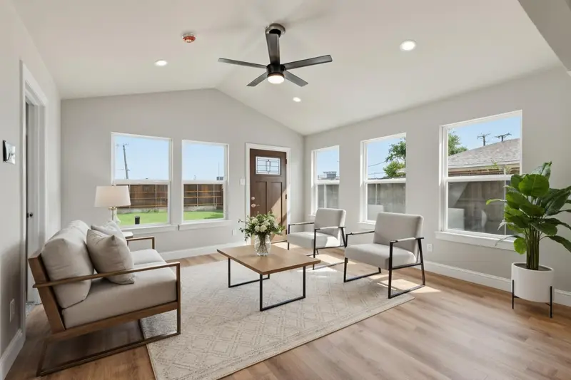 Virtually staged second living space with a vaulted ceiling and a wall of windows